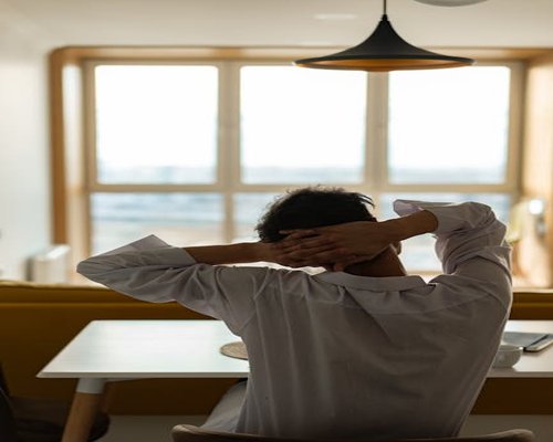A person stretching gently by the window during a work break